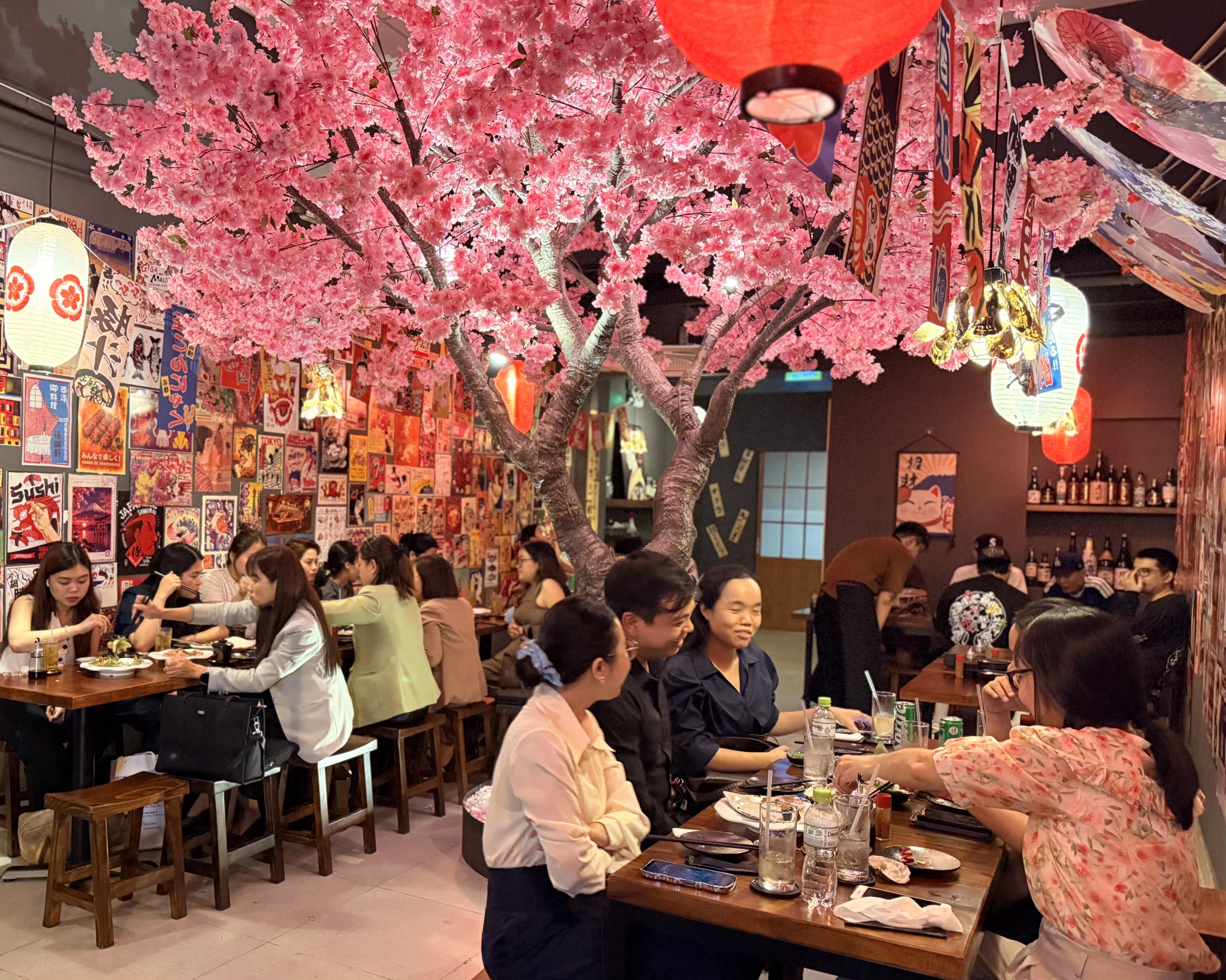 Tầng 2 EN Izakaya với cây sakura trung tâm và bàn nhóm